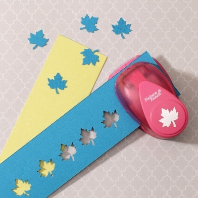 Furador de papel rosa em formato de folha e papel azul furado com motivos de folhas
