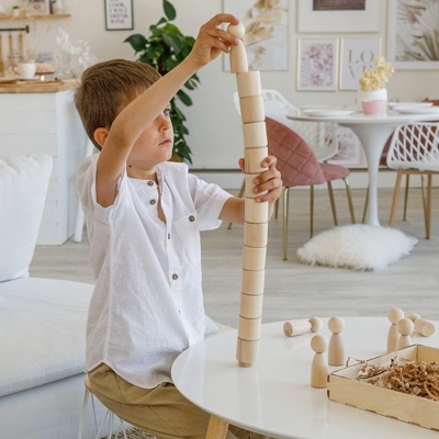 Criança a empilhar blocos de madeira numa mesa branca numa sala moderna