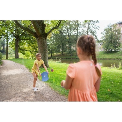 Duas crianças a brincar ao ar livre num parque com árvores e lago ao fundo