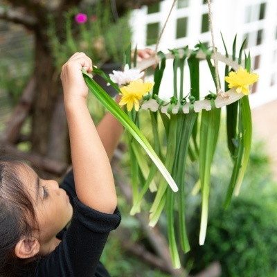Criança a segurar coroa circular de folhas e flores ao ar livre