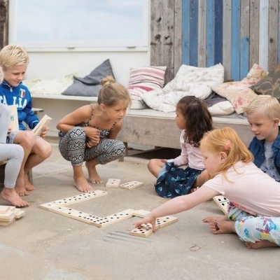 Crianças a jogar jogo de peças de madeira ao ar livre na areia