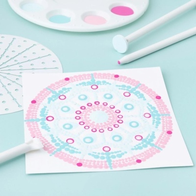 Stencil redondo perfurado e desenho circular azul e rosa com pincéis e paleta de tinta