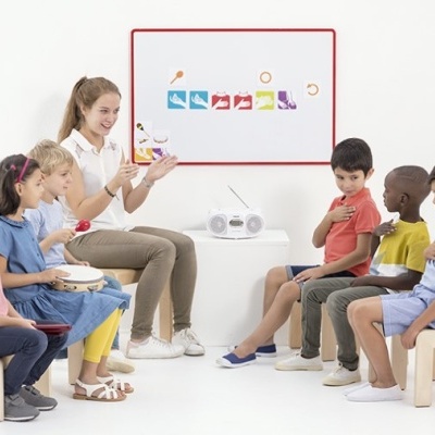 Crianças e professora com instrumentos musicais e cartões coloridos em sala clara