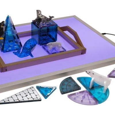 Tabuleiro iluminado com blocos azuis transparentes e peças geométricas coloridas.