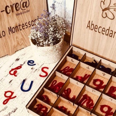 Caixa de madeira com letras do alfabeto Montessori e vaso com flores secas