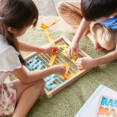 Crianças a brincar com brinquedo de madeira e fitas coloridas num tapete verde