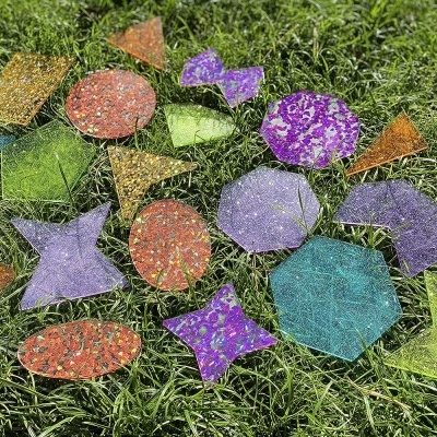 Peças coloridas translúcidas em várias formas geométricas sobre relva