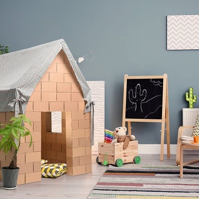 Tenda infantil em formato de casinha feita com blocos de madeira e tecido cinza num quarto azul com acessórios de criança.