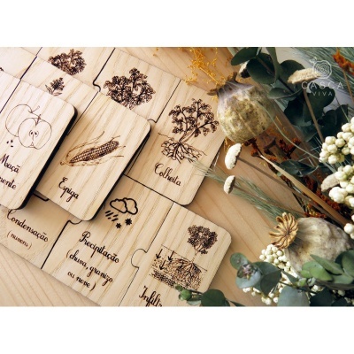 Cartas de madeira ilustradas com alimentos e texto, em cima de superfície de madeira com flores secas