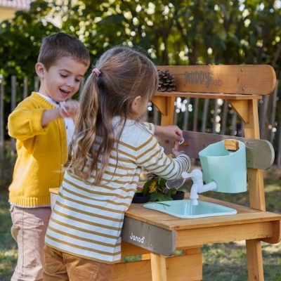 Brinquedo de cozinha infantil em madeira com pia, torneira e balde azul, duas crianças a brincar no exterior