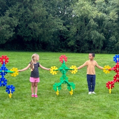 Crianças com figuras de peças de plástico interligadas num campo verde