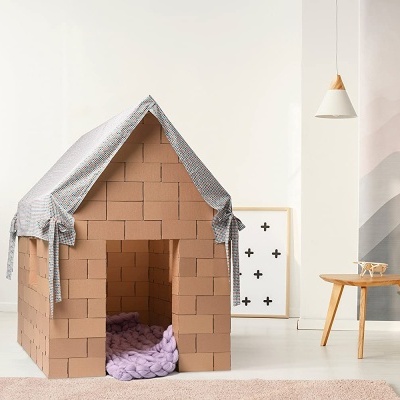 Casota infantil de tecido com padrão cinza e interior com padrão de tijolos laranja em sala clara