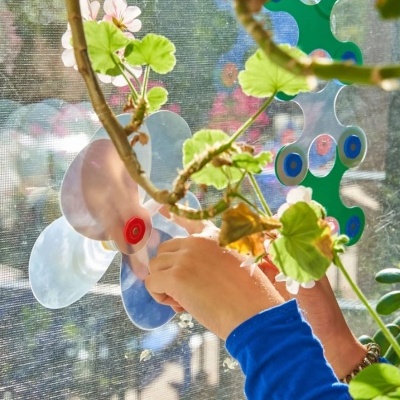 Criança a aplicar decalques em sol de janela com formas de flores coloridas