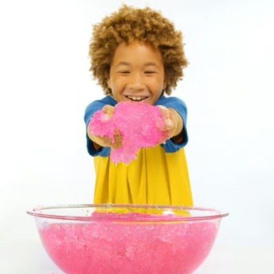 Criança a mostrar líquido pegajoso cor-de-rosa acima de taça transparente