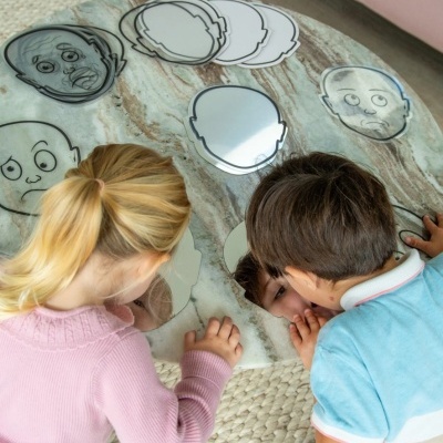 Crianças a brincar com placas em forma de cabeça com expressões desenhadas