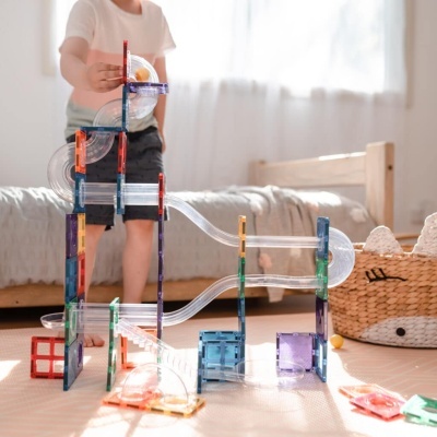 Brinquedo de construção com tubos transparentes e peças coloridas em quarto infantil