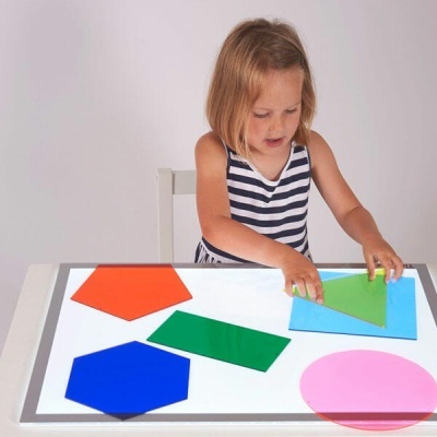 Criança com formas geométricas coloridas em superfície luminosa