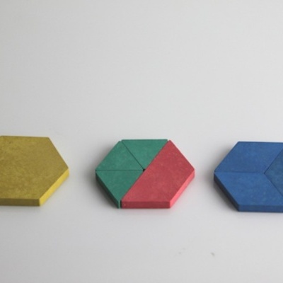 três formas hexagonais em madeira colorida sobre superfície branca