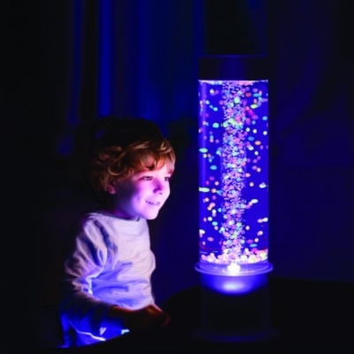 Lâmpada de bolhas LED cilíndrica com luzes coloridas e base branca num quarto escuro