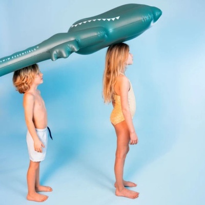 Crianças com bóia insuflável em forma de tubarão