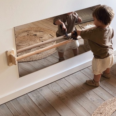 Espelho com barras de madeira e criança a brincar