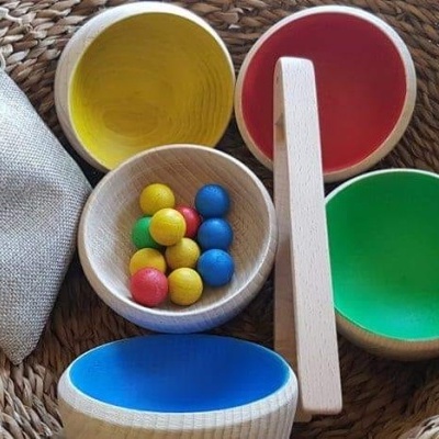 Conjunto de brinquedos de madeira coloridos em cesto de vime com saco de pano cinza