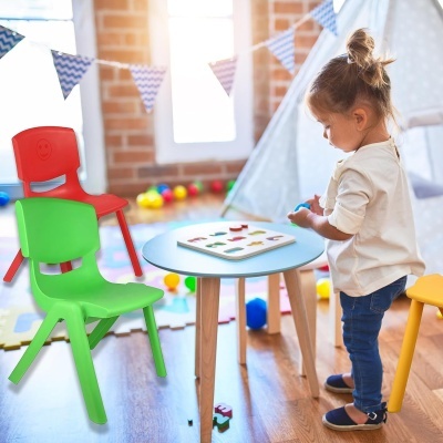 Mesa azul com cadeiras coloridas em sala infantil com criança a brincar
