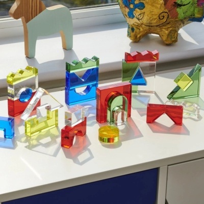 Blocos de construção coloridos translúcidos em várias formas geométricas sobre superfície branca junto a janela