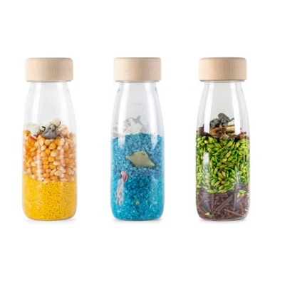 Três frascos de vidro com tampa de madeira contendo diferentes materiais coloridos e objetos decorativos.