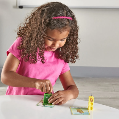 Criança com brinquedos de blocos verdes e amarelos numa mesa branca