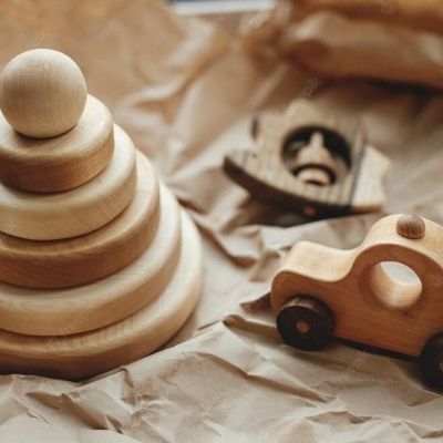 Brinquedos de madeira natural: empilhador de discos, carro e barco sobre papel castanho amassado