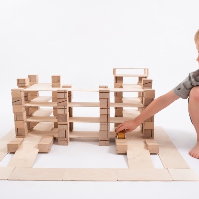 Menino a brincar com blocos de madeira formando uma estrutura.