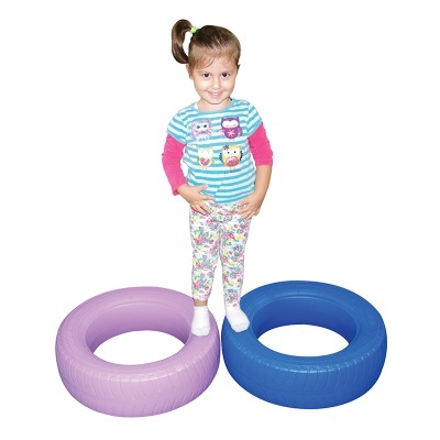 Criança entre dois pneus de plástico lilás e azul em fundo branco
