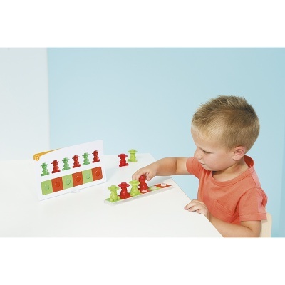 Criança a brincar com jogo de tabuleiro de ursos vermelhos e verdes numa mesa branca