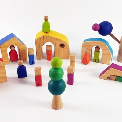 Brinquedos de madeira coloridos com formas de árvores, casas e figuras humanas