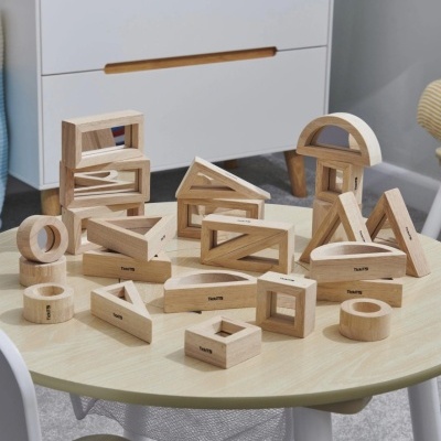 Blocos de madeira natural variados empilhados numa mesa redonda clara com a palavra TRAUTO