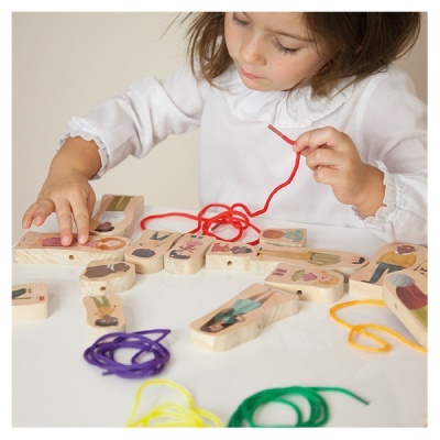 Criança a brincar com brinquedo de madeira e cordões coloridos.