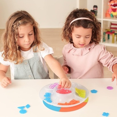 Duas crianças a jogar com brinquedo colorido de plástico numa mesa branca