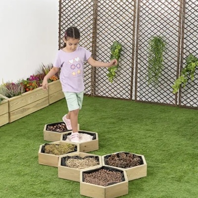 Passadiço sensorial de madeira com materiais naturais em ambiente interior de relva artificial