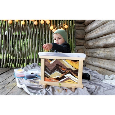 Bebé com estrutura de madeira e painel colorido com padrões ondulados ao ar livre
