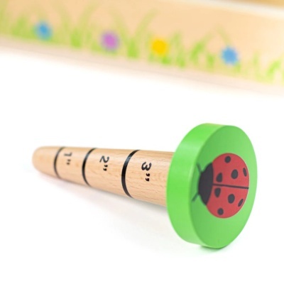 Objeto cilíndrico de madeira com marcações numeradas e extremidade verde com joaninha
