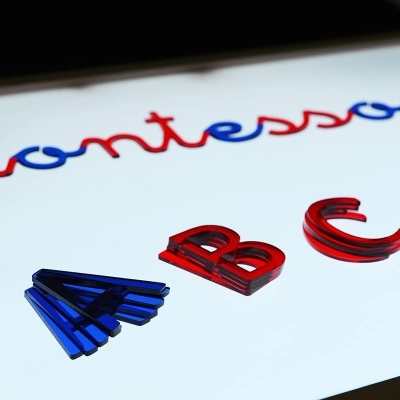 Letras coloridas 'montessori' e letras 'A', 'B', 'C', 'D' em plástico sobre superfície iluminada