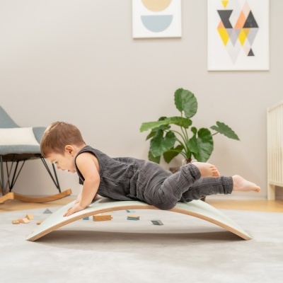 Criança a brincar numa tábua de equilíbrio de madeira num quarto com decoração moderna