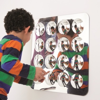 Painel sensorial de parede com espelhos convexos redondos refletindo um menino