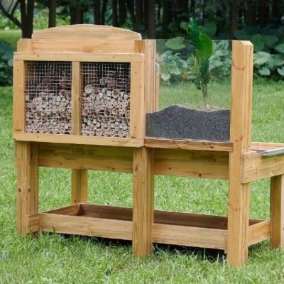 Mesa de cultivo em madeira com painel de rede e planta num jardim