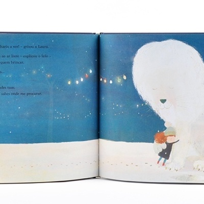Livro infantil aberto com ilustração de personagem abraçando animal branco grande sob lua e luzes