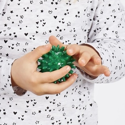 Criança com camisola branca e preta segurando bola verde texturada