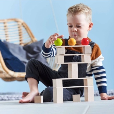 Menino a brincar com blocos de madeira e bolas coloridas