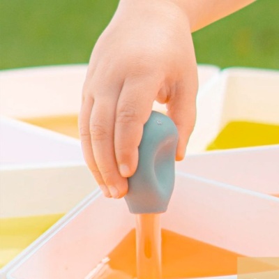 Mão infantil a pintar com pincel em tinta laranja