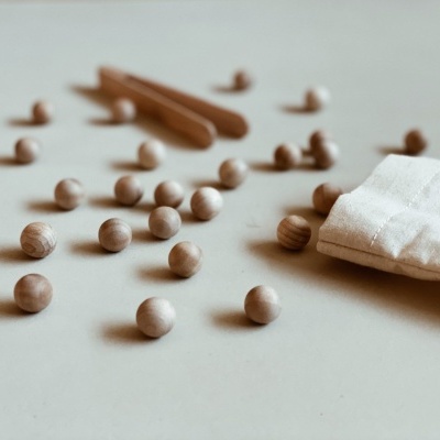 Bolas de madeira e saco branco sobre superfície clara